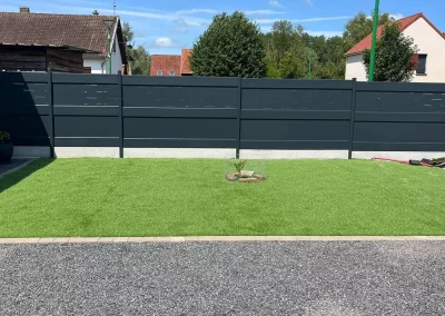 Clôture aluminium anthracite à lames ajourées en partie haute autour d'un jardin dans la Somme