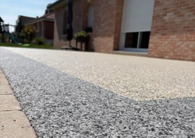 Terrasse et trottoir en moquette de pierre ivoire doré et bleu turquin le long d'une maison en brique, Somme